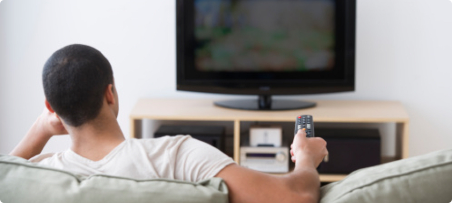 Man sitting on couch pointing a remote at a TV screen