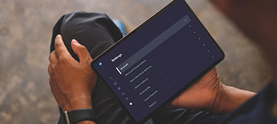 A person holds a tablet in their lap